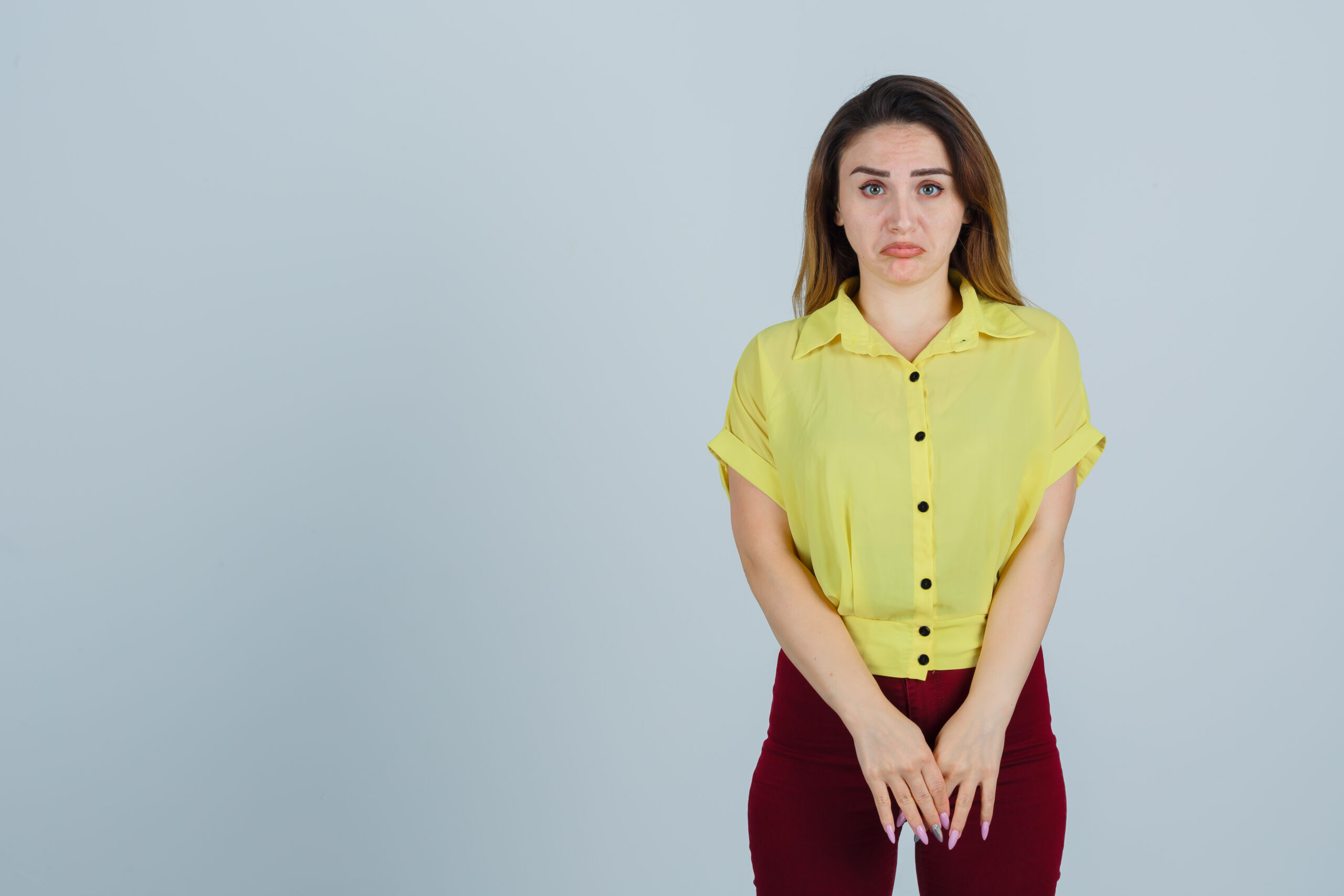 Young woman standing with a worried expression, representing possible burning during urination or STD symptoms.