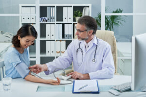 Doctor measuring a female patient's blood pressure during a routine health checkup in a medical clinic.