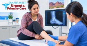 Patient receiving an ankle examination with a digital foot X-ray displayed on a monitor at Sahara West Urgent & Primary Care.