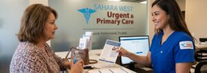 A friendly healthcare staff member at Sahara West Urgent & Primary Care counter handing a patient an informational pamphlet titled "Preparing for Your Diabetes Screening".